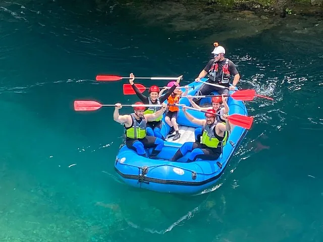 Draufsicht auf eine Familie beim Rafting auf klarem blauem Wasser.