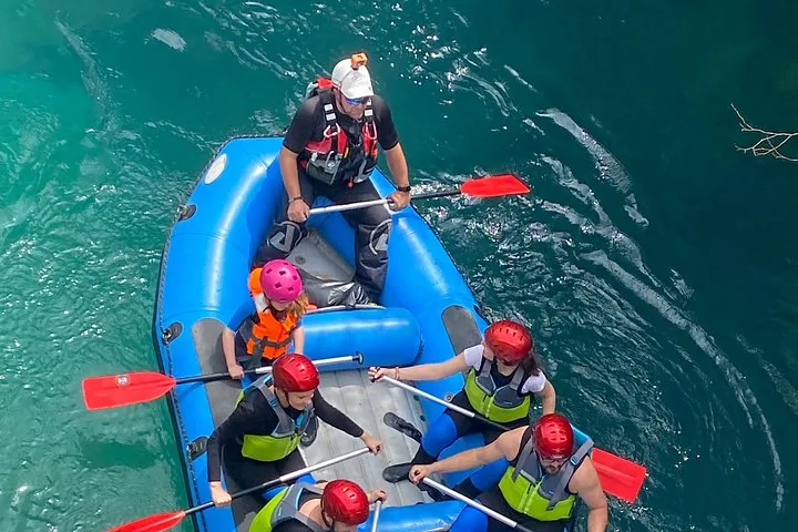 Eine Familie mit Paddeln in einem blauen Raft auf dem Fluss.